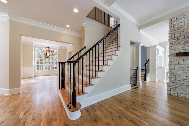 stairway featuring a notable chandelier, baseboards, crown molding, and wood finished floors