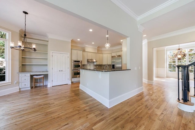 kitchen featuring stainless steel appliances, light wood-style flooring, a chandelier, and a healthy amount of sunlight