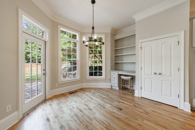 unfurnished living room featuring light wood-style flooring, crown molding, baseboards, and a notable chandelier