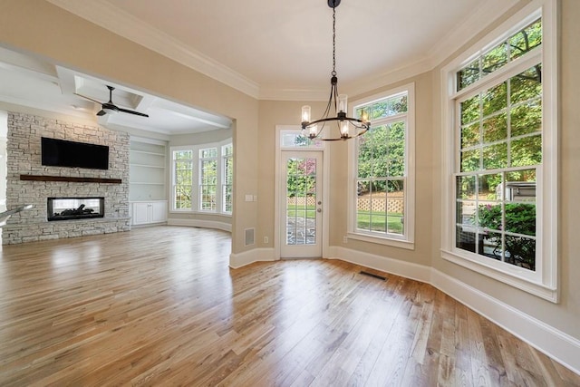 unfurnished living room featuring hardwood / wood-style floors, a stone fireplace, crown molding, baseboards, and built in shelves