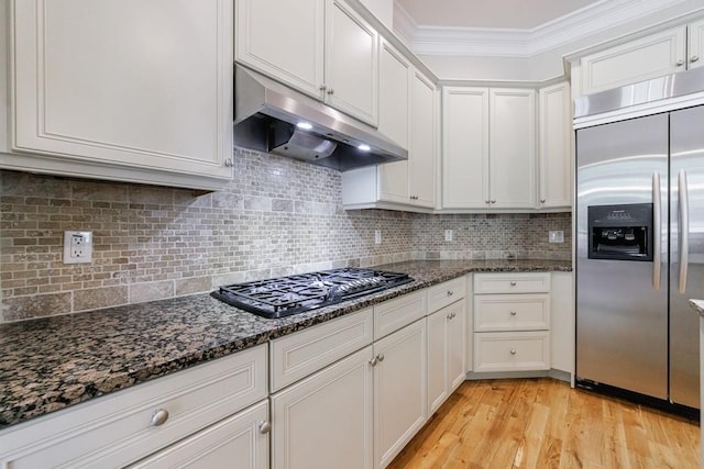 kitchen with white cabinets, under cabinet range hood, built in refrigerator, crown molding, and black gas stovetop