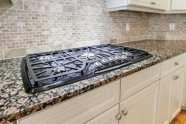 kitchen featuring dark stone counters, decorative backsplash, and black gas stovetop