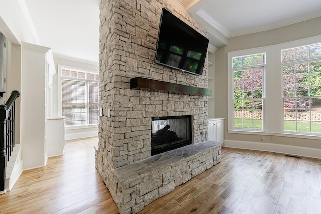 unfurnished living room with visible vents, crown molding, baseboards, a fireplace, and light wood-style flooring
