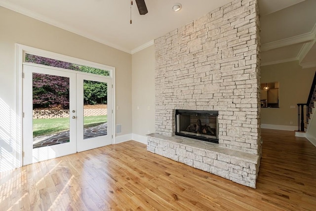 unfurnished living room with a ceiling fan, crown molding, stairs, wood finished floors, and a fireplace
