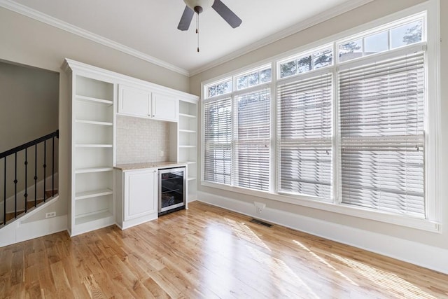 unfurnished living room featuring baseboards, visible vents, light wood finished floors, and wine cooler