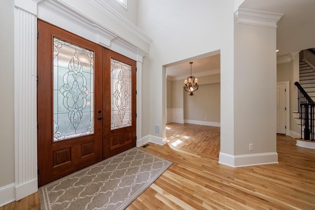 foyer entrance featuring wood finished floors, french doors, crown molding, baseboards, and stairs
