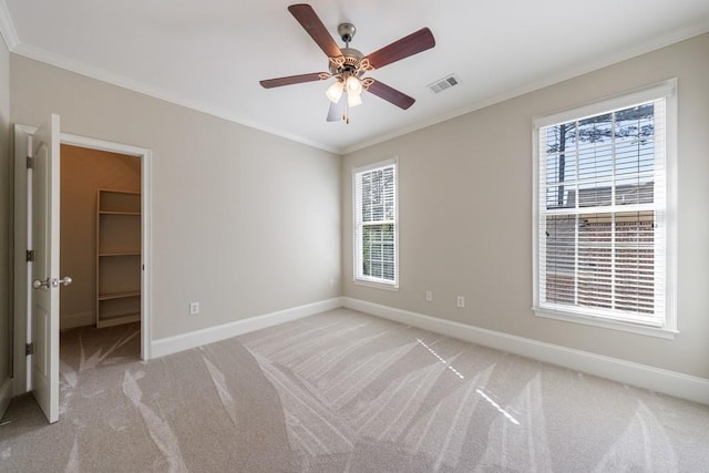 unfurnished bedroom featuring crown molding, multiple windows, light colored carpet, baseboards, and visible vents