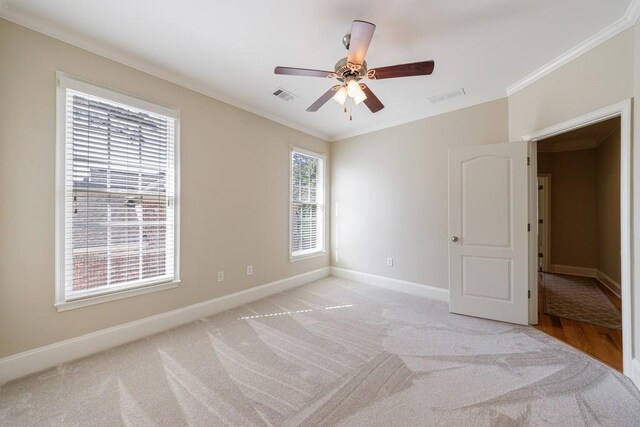 unfurnished room with baseboards, crown molding, and visible vents
