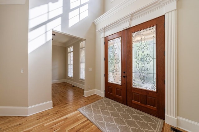 foyer featuring crown molding, light wood-type flooring, french doors, baseboards, and visible vents