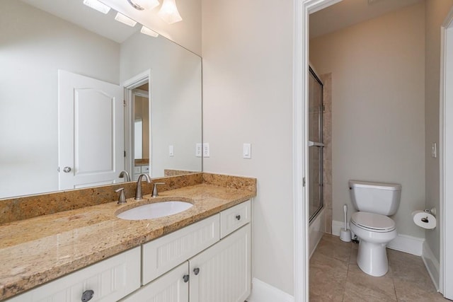 bathroom with baseboards, vanity, combined bath / shower with glass door, and toilet