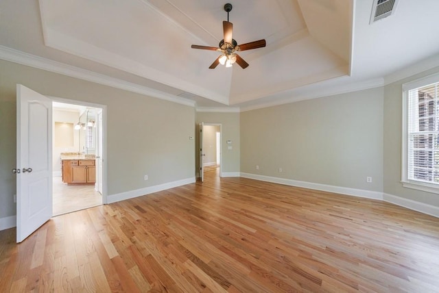 unfurnished bedroom with baseboards, a tray ceiling, visible vents, and light wood-style flooring