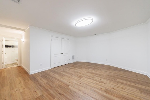 interior space featuring light wood-type flooring, baseboards, visible vents, and crown molding
