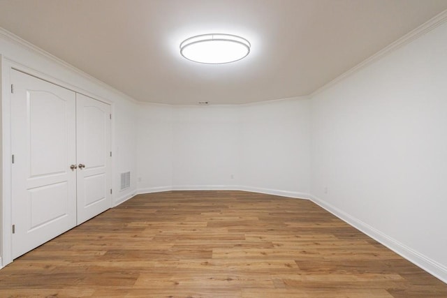 unfurnished bedroom with crown molding, a closet, light wood finished floors, baseboards, and visible vents
