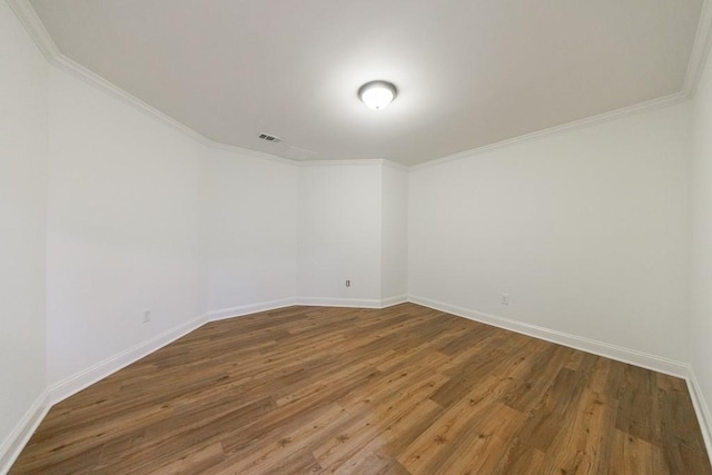 empty room with baseboards, crown molding, and wood finished floors