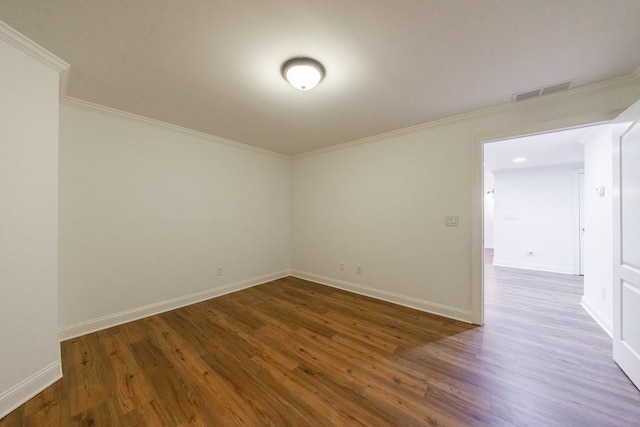 spare room with baseboards, ornamental molding, wood finished floors, and visible vents