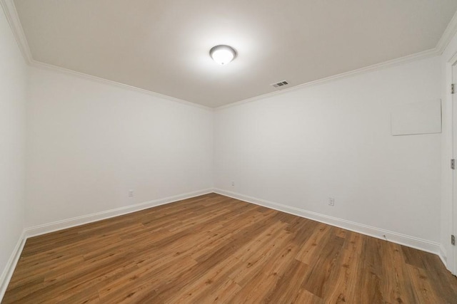 unfurnished room featuring wood finished floors, visible vents, baseboards, and ornamental molding