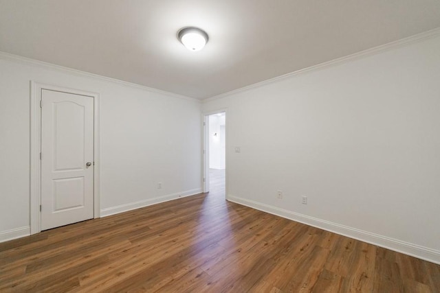 spare room featuring baseboards, wood finished floors, and crown molding