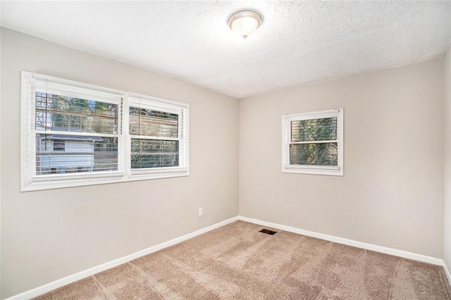 carpeted empty room featuring a textured ceiling