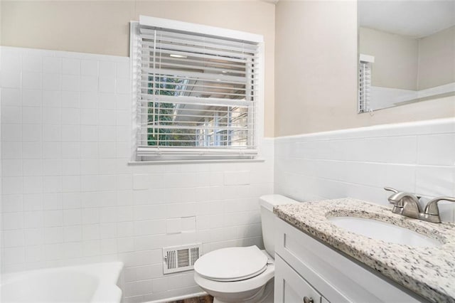 bathroom with tile walls, toilet, a bathing tub, and vanity