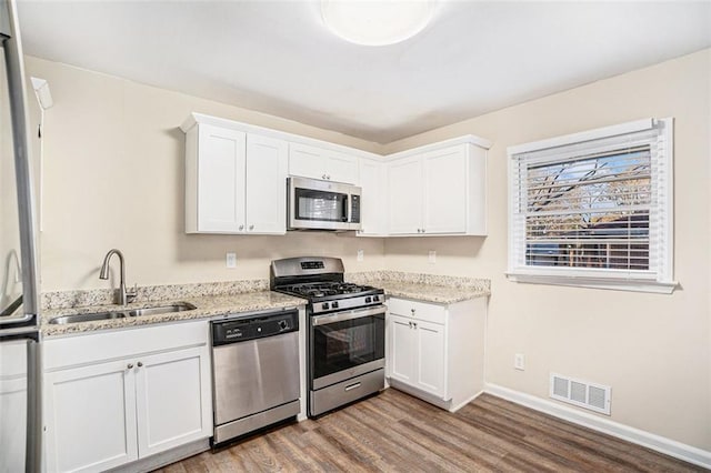 kitchen featuring sink, light stone countertops, white cabinets, and appliances with stainless steel finishes