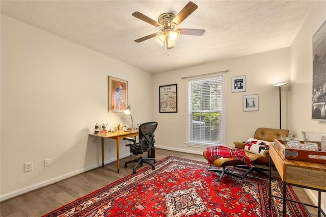office area featuring baseboards, a textured ceiling, ceiling fan, and wood finished floors