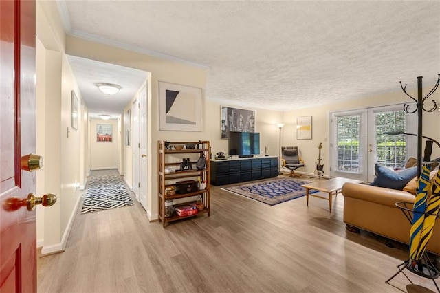 living area with crown molding, a textured ceiling, baseboards, and light wood-type flooring