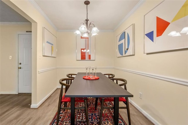 dining room featuring crown molding, baseboards, wood finished floors, and a chandelier