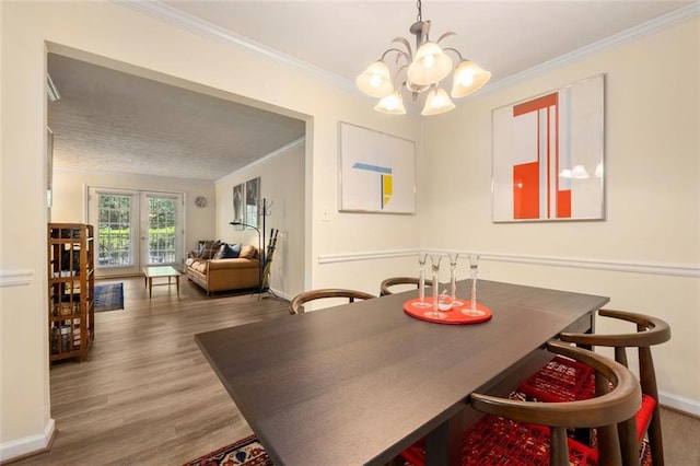 dining room with baseboards, a chandelier, ornamental molding, and wood finished floors