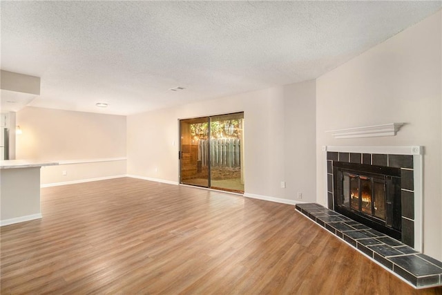 unfurnished living room with a textured ceiling, a fireplace, and wood-type flooring