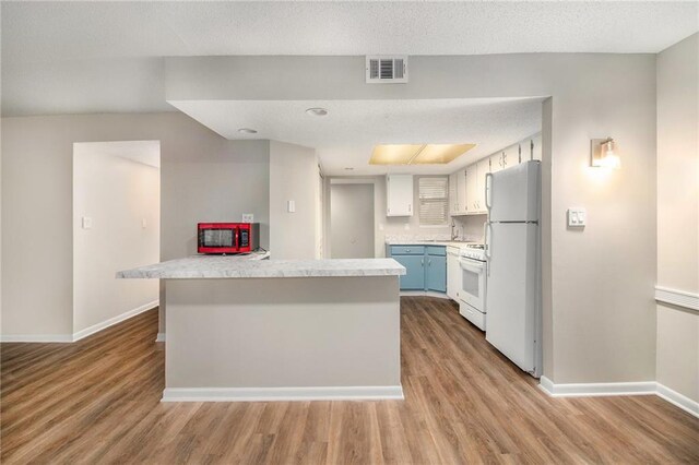 kitchen featuring blue cabinets, white cabinets, a center island, white appliances, and light hardwood / wood-style flooring