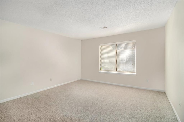 carpeted empty room featuring a textured ceiling