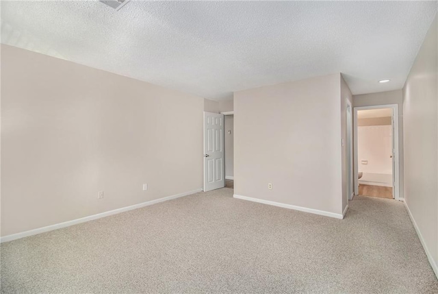 spare room featuring light carpet and a textured ceiling