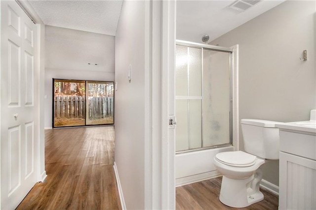 full bathroom with hardwood / wood-style flooring, enclosed tub / shower combo, vanity, and toilet