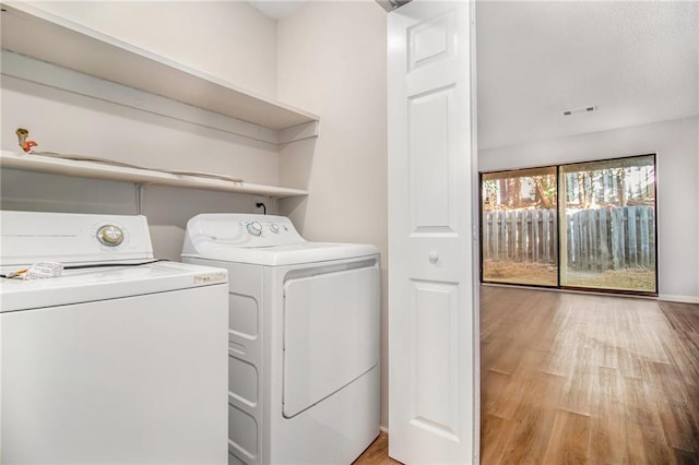 laundry area with washer and dryer and light wood-type flooring