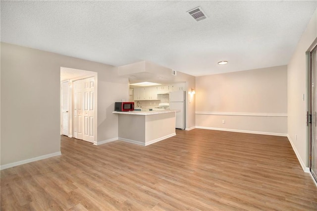 unfurnished living room with light hardwood / wood-style flooring and a textured ceiling