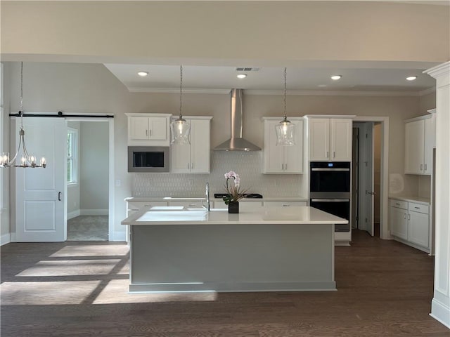 kitchen with wall chimney range hood, backsplash, dark wood-style flooring, stainless steel microwave, and crown molding
