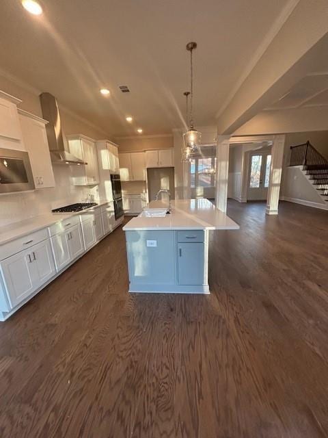 kitchen with wall chimney exhaust hood, a sink, gas stovetop, dark wood finished floors, and recessed lighting