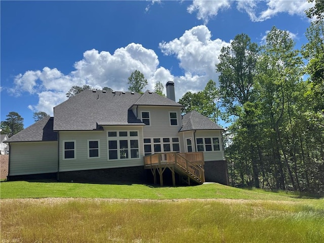 back of house featuring stairway, a chimney, a lawn, a deck, and a shingled roof