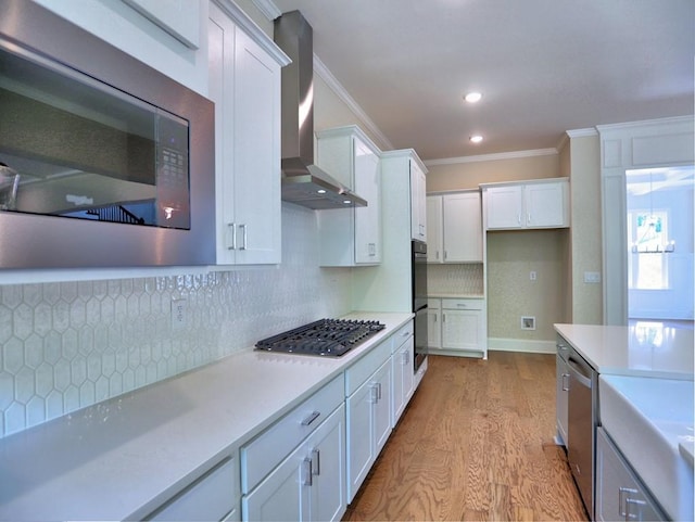 3730 Reserve Overlook Way, Cumming, GA 30041 - kitchen with appliances with stainless steel finishes, wall chimney exhaust hood, crown molding, light wood finished floors, and white cabinets