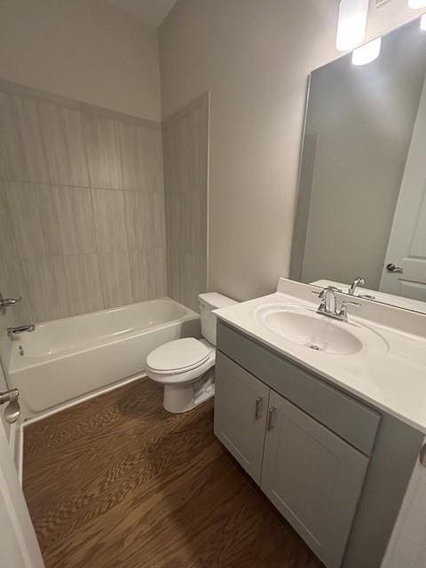 bathroom featuring wood finished floors, toilet, vanity, and washtub / shower combination