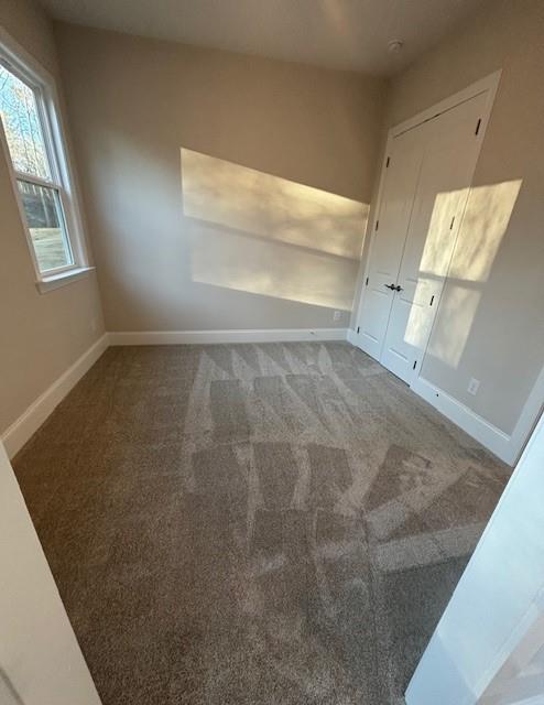 spare room featuring baseboards and carpet flooring