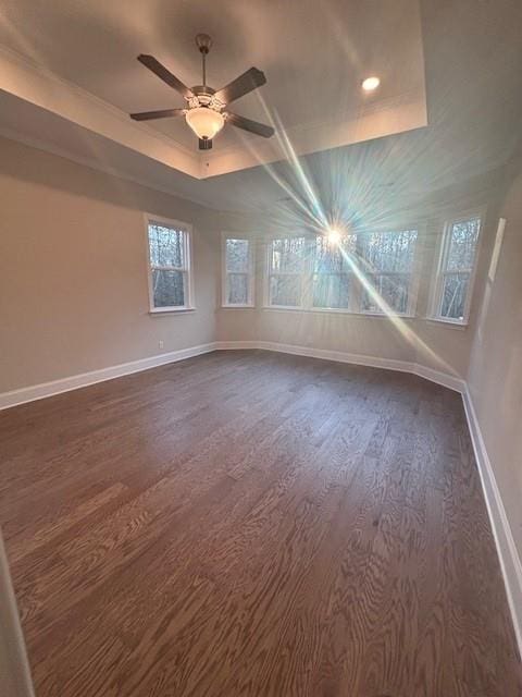 spare room with dark wood-style flooring, baseboards, ceiling fan, a tray ceiling, and recessed lighting