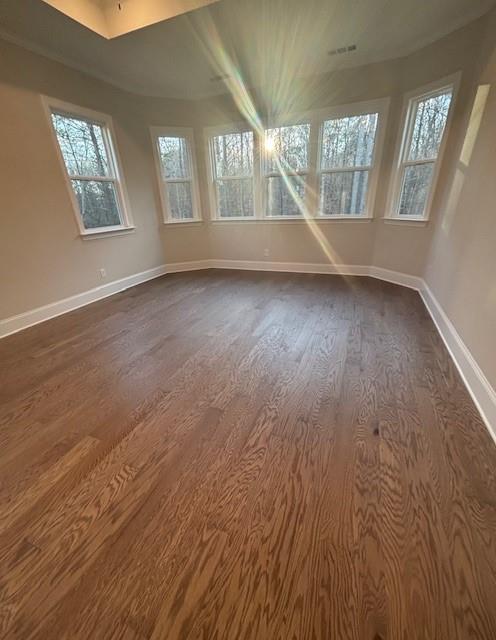 spare room featuring dark wood-style flooring and baseboards