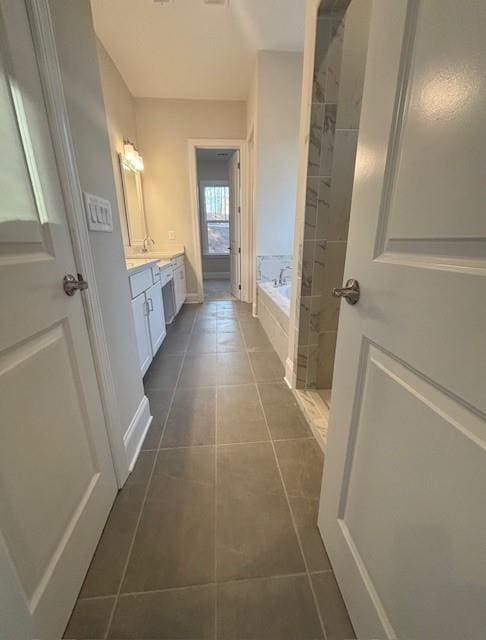 full bath with tile patterned flooring, a garden tub, and vanity