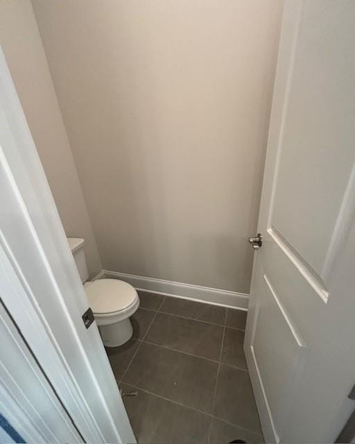 bathroom featuring baseboards, toilet, and tile patterned flooring
