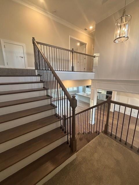 stairs featuring crown molding, a chandelier, and recessed lighting