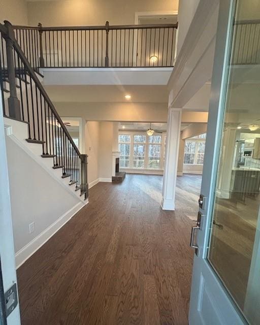 entrance foyer with wood finished floors, baseboards, stairs, ceiling fan, and a towering ceiling