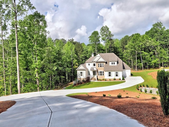 3730 Reserve Overlook Way, Cumming, GA 30041 - view of front of house with curved driveway, a front yard, a forest view, a chimney, and stone siding