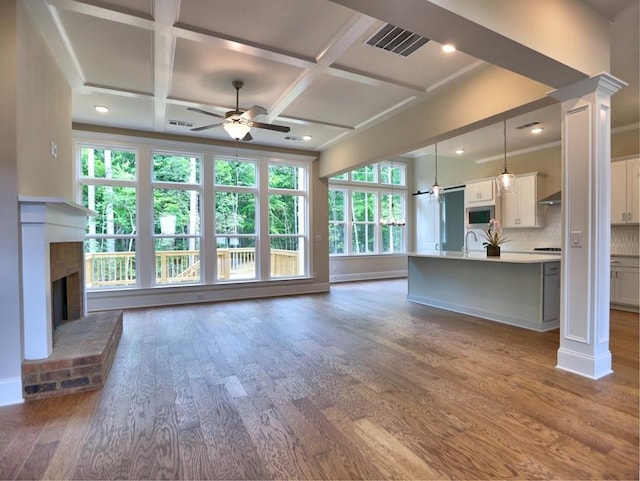 3730 Reserve Overlook Way, Cumming, GA 30041 - unfurnished living room featuring ceiling fan, coffered ceiling, dark wood-style flooring, ornate columns, and a brick fireplace