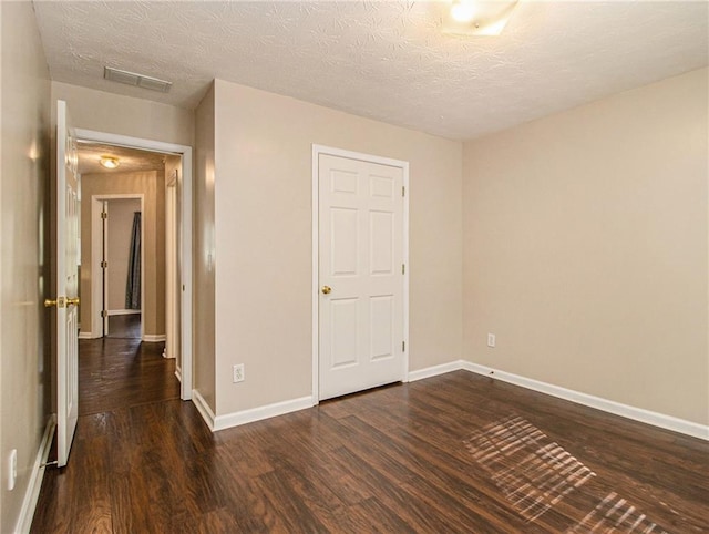 unfurnished bedroom with a textured ceiling and dark wood-type flooring